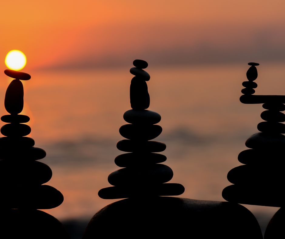 a tower of balanced pebbles on a beach at sunset